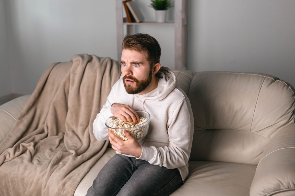 Man watching movies sitting on a couch at home